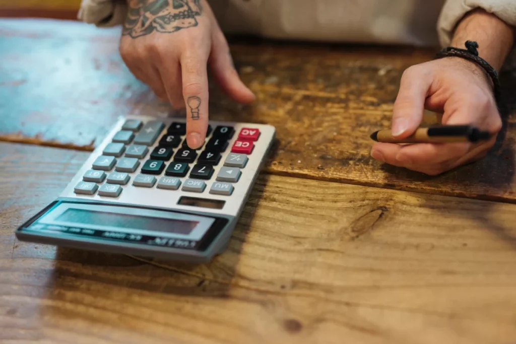 homem-jovem-segurando-caneta-usando-calculadora-em-sua loja-preço de venda