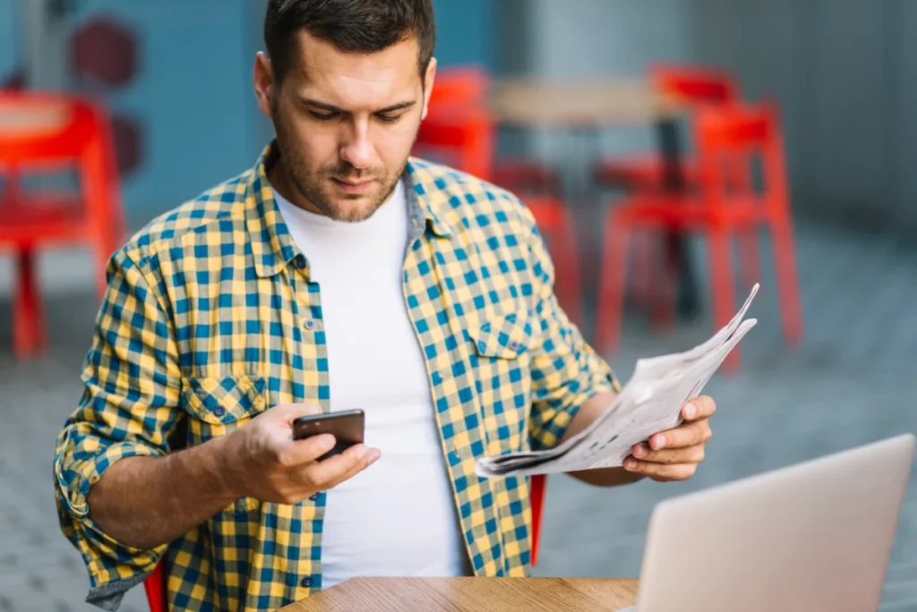 homem-posando-com-telefone-e-jornal-como se calcula o simples nacional