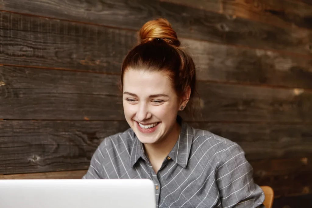 mulher-ruiva-com-o-cabelo-preso-sorrindo-ao-mexer-no-computador-como-vender-com-estrategias-rapidas