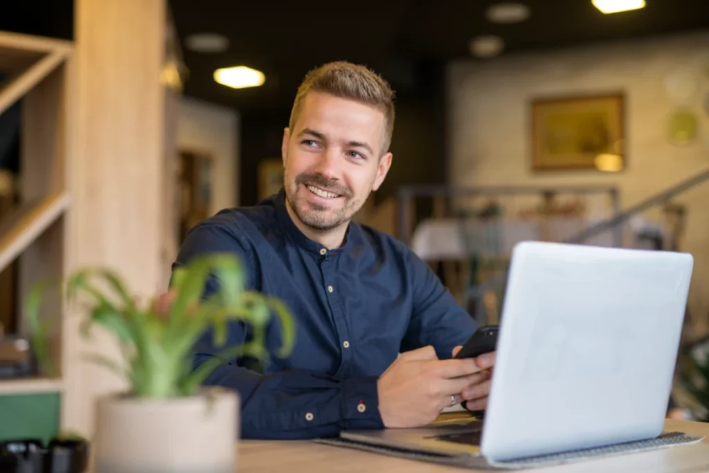 homem de negócios sentado num café bar usando computador e olhando ao lado como vender um produto