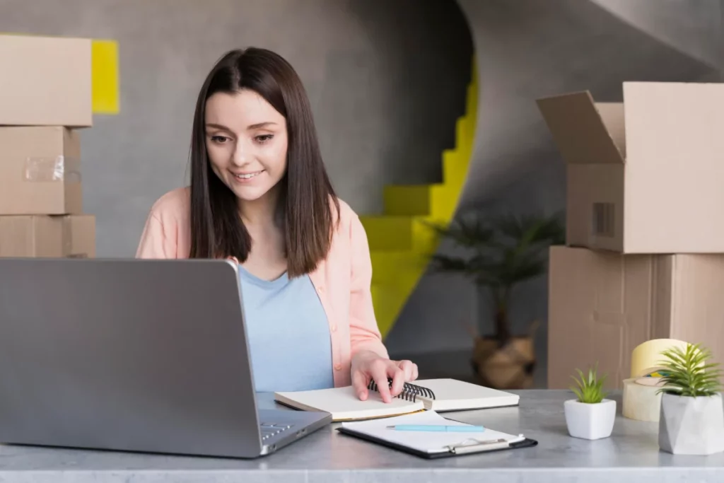 vista frontal de mulher mexendo em notebook enquanto está rodeada de caixas vendas online como começar