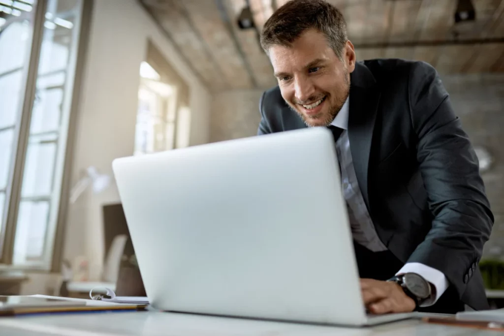 empreendedor feliz e bem vestido trabalhando em pé no computador em escritório - plataforma de venda online