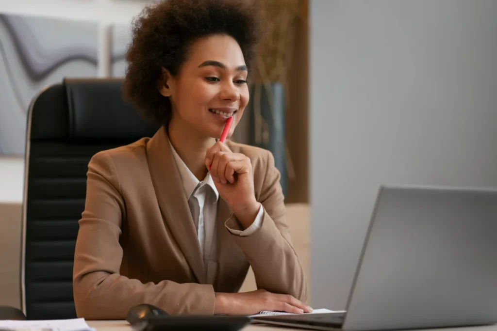 empreendedora negra feliz e bem vestida trabalhando no computador em escritório - plataforma de venda online