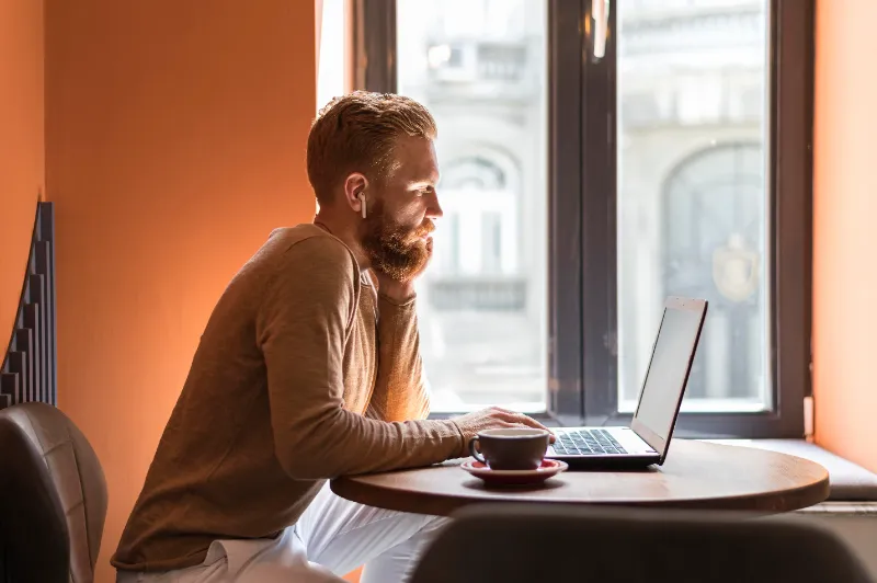 vista lateral de homem sentado trabalhando ao computador com café ao lado - produtos mais vendidos na shopee