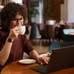 mulher tomando café enquanto trabalha de casa sentada no computador - produtos mais vendidos na shopee