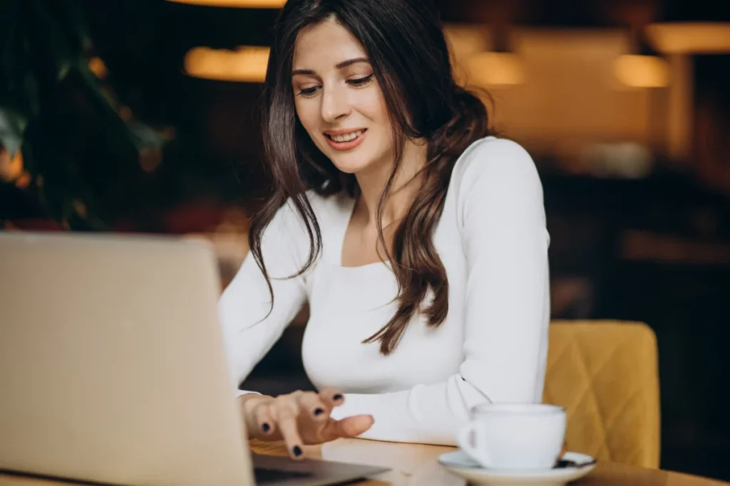 mulher trabalhando em computador na mesa de um café - o que é newsletter