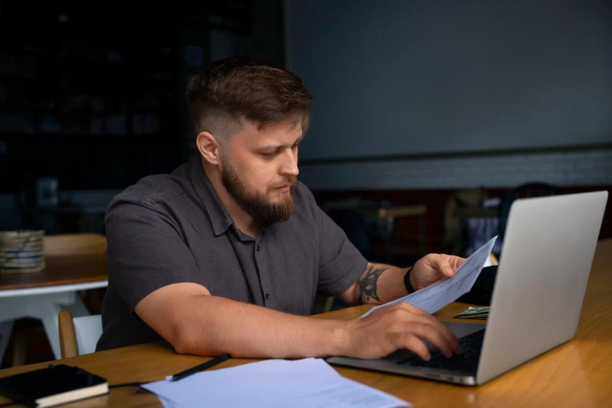 homem mexendo no computador enquanto olha folha de papel - amazon marketplace