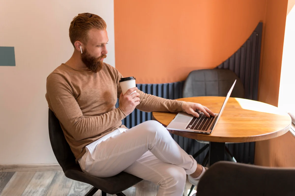 homem sentado com café na mão enquanto mexe no computador -amazon marketplace