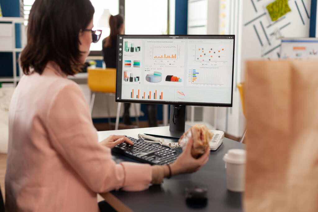 Empreendedora analisando dashboard de e-commerce em computador com gráficos de vendas e pedidos