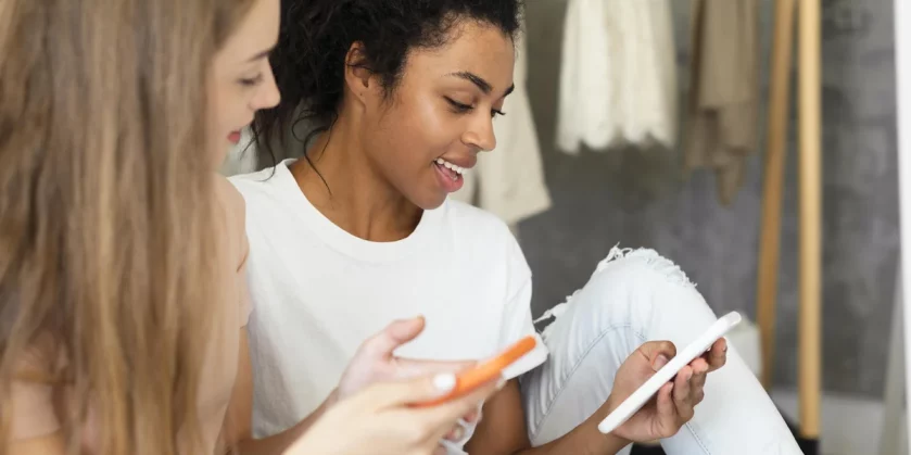 side-view-female-friends-looking-their-smartphones (1)